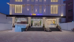 A modern hotel entrance with a 'Click Collection' sign, a reception desk, and a staircase leading to the lobby. - Click Collection Ayodhya (Ayodhya)