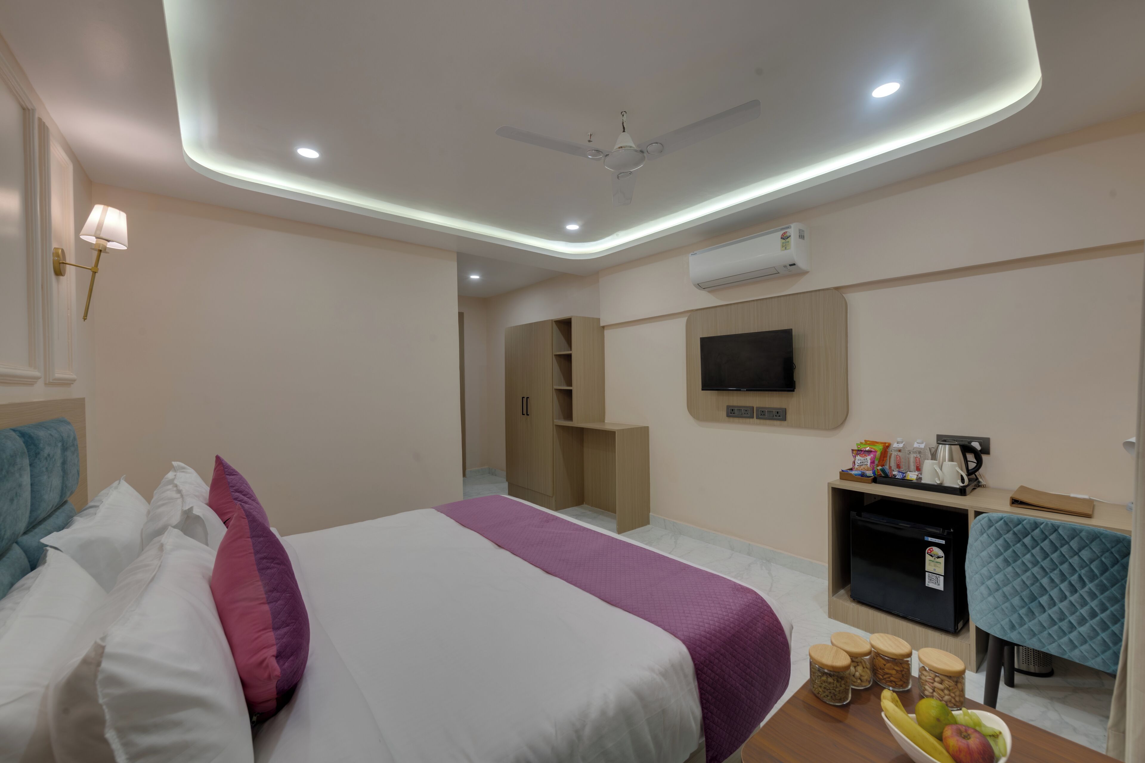 Une chambre d’hôtel équipée d’un lit, d’un bureau avec un ordinateur, d’une télévision et d’un mini-bar.