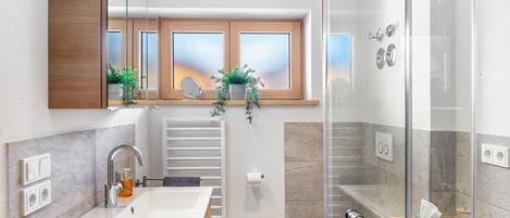 Ein modernes Badezimmer mit großem Spiegel, Waschbecken, Toilette und Duschbereich.