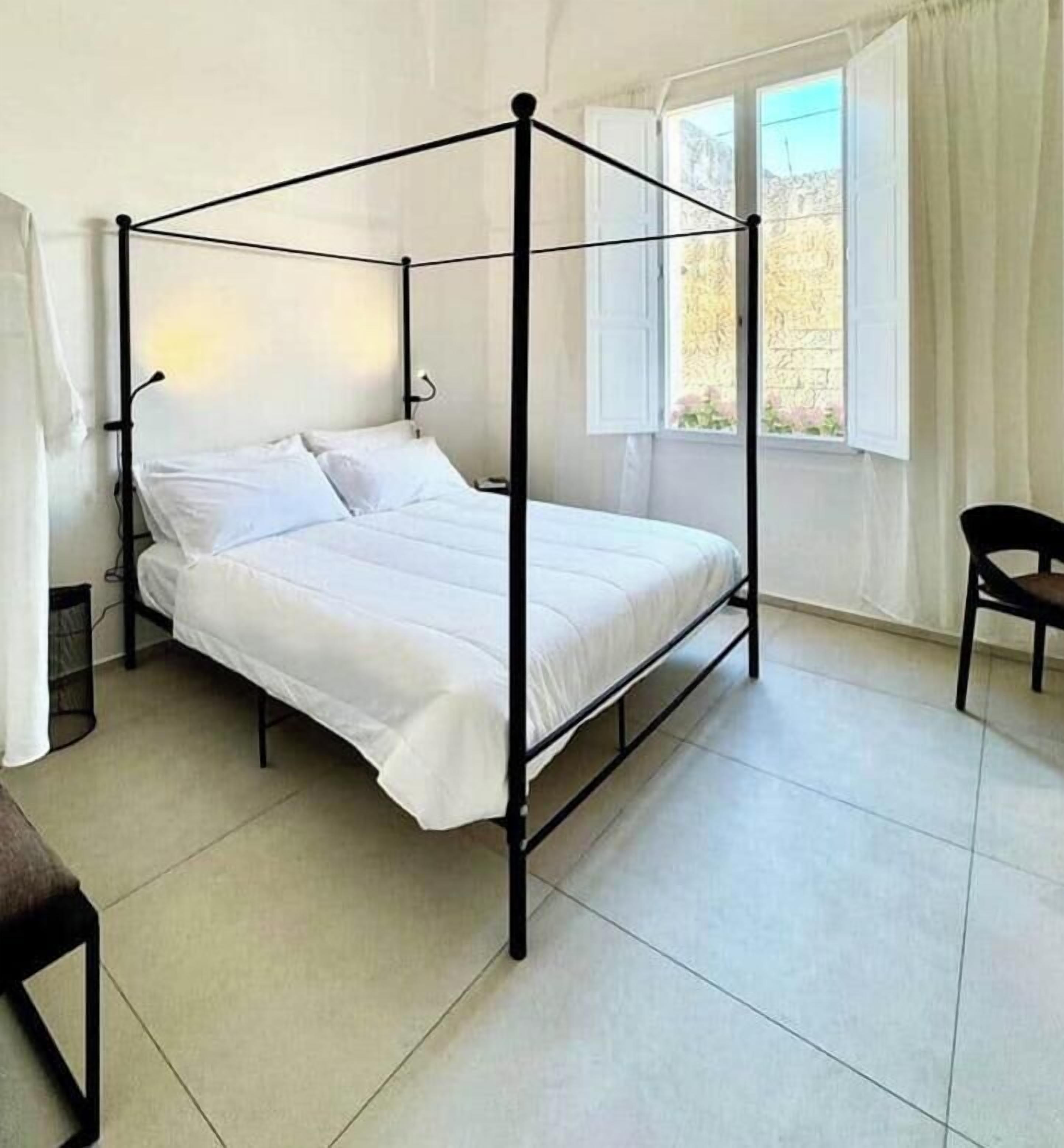 Un lit à baldaquin dans une pièce dotée d’une fenêtre et d’une chaise.