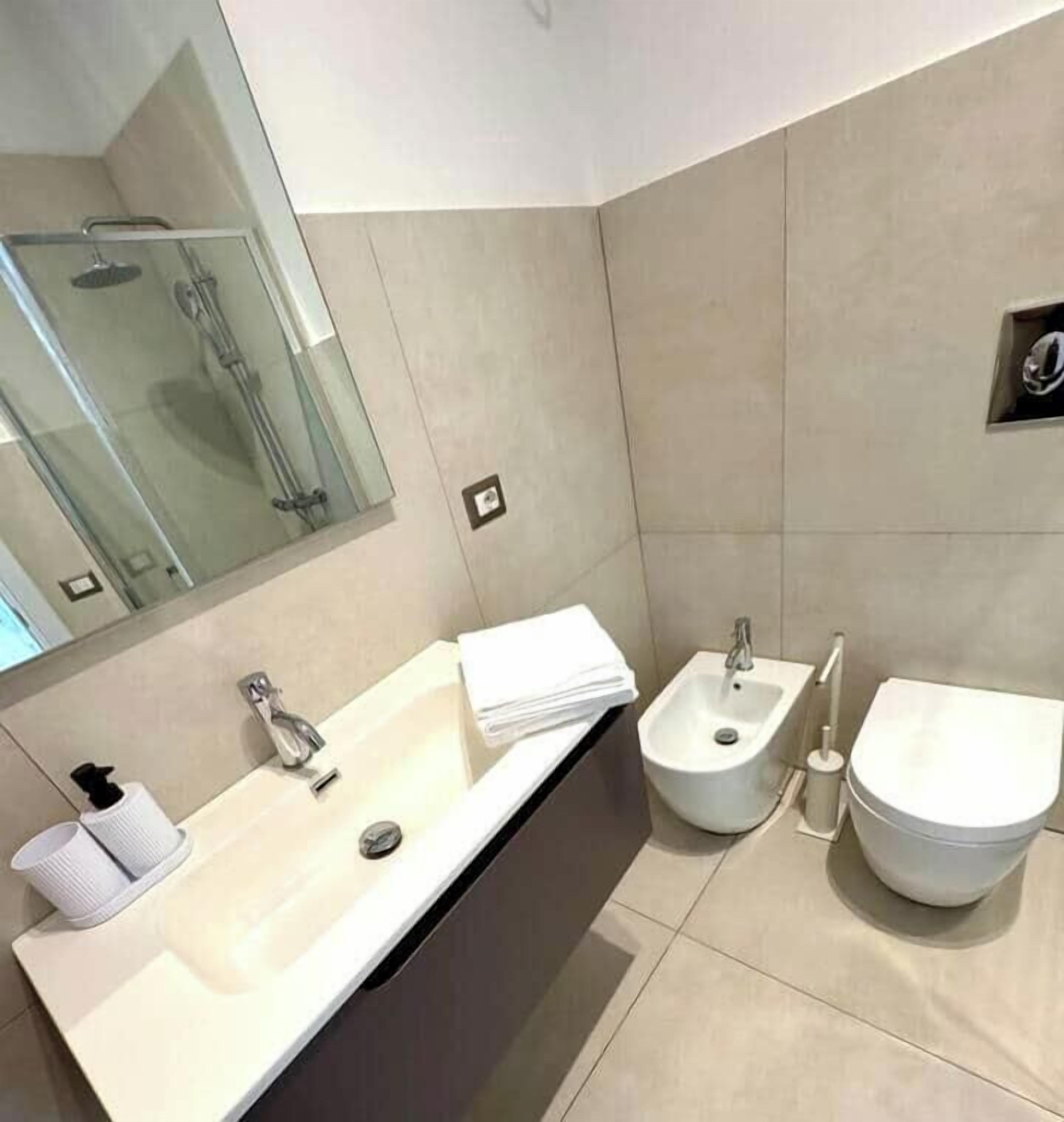 A modern bathroom with a large sink, bidet, and toilet.