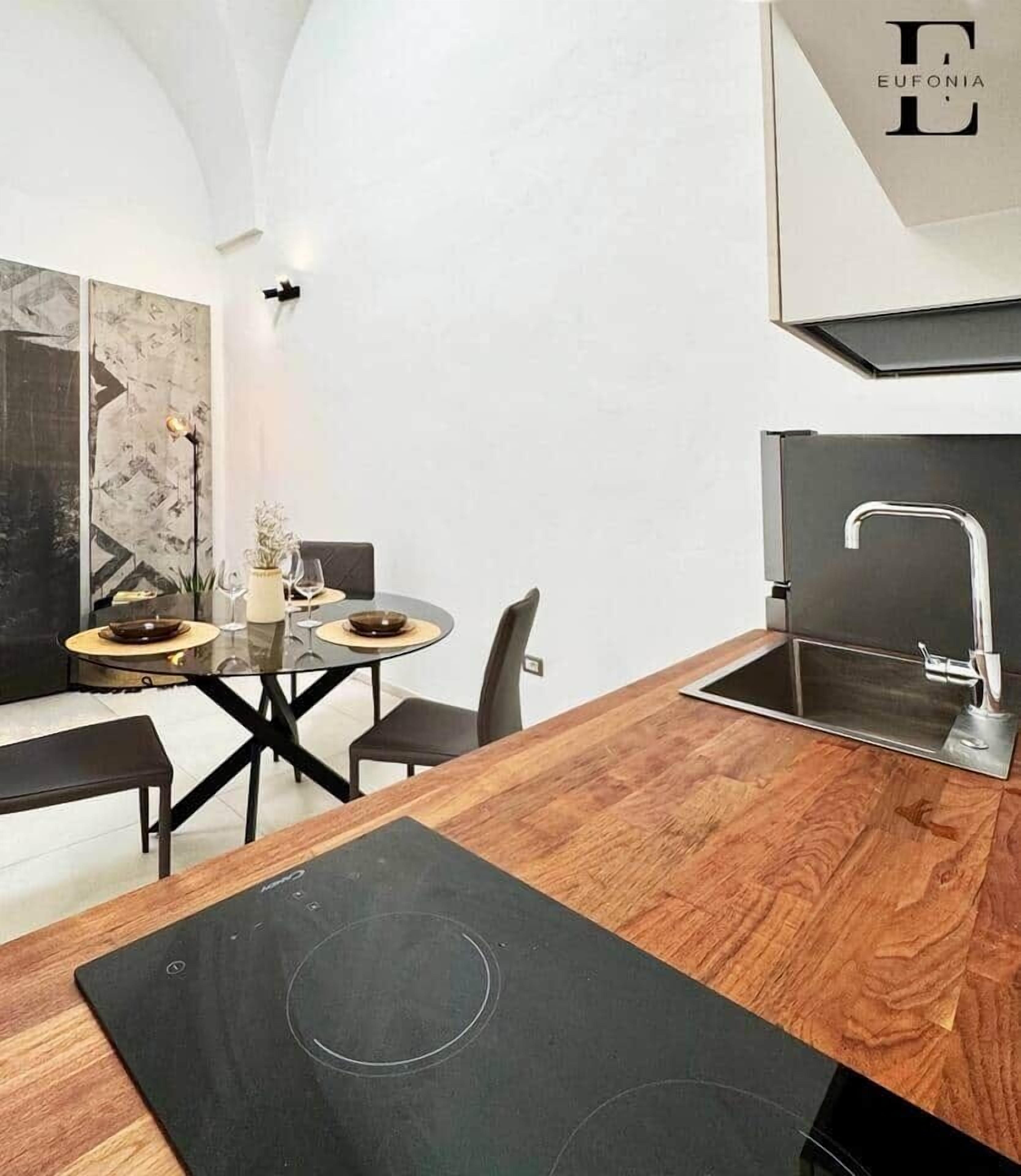 Une cuisine moderne dotée d’un plan de travail en bois, d’une plaque de cuisson à induction noire et d’un robinet en acier inoxydable.