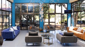 A modern lobby with large windows, multiple sofas, and a central coffee table. - Sigelege Beach Resort (Senga)
