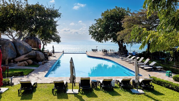 A pool area with lounge chairs and a view of the sea. - Sigelege Beach Resort (Senga)
