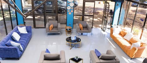 A spacious lobby with a blue and orange sofa set, a coffee table, and a decorative pillar.
