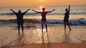 Three people standing on a beach facing the sunset. - Sigelege Beach Resort (Senga)