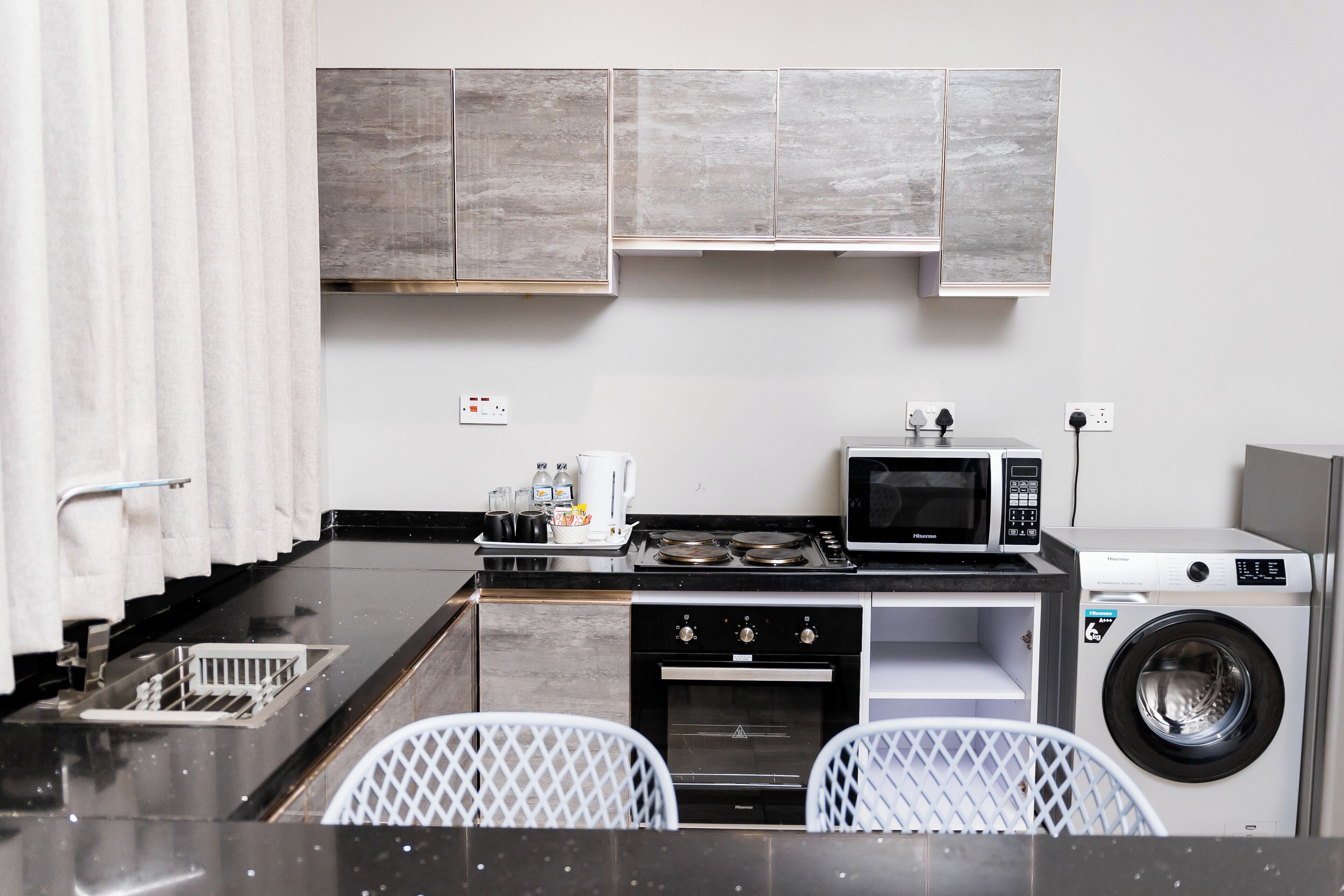 A compact kitchen with a microwave, stove, oven, and washing machine.