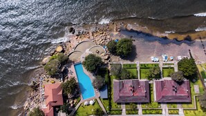 An aerial view of a coastal property with a swimming pool, beach area, and several buildings. - Sigelege Beach Resort (Senga)