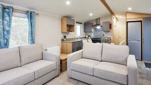 A compact living space with two sofas, a kitchen area, and a door leading to a bathroom.