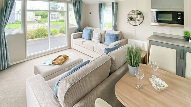 A modern living room with a sofa, a dining table, and a kitchen area.
