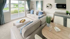 Ein modernes Wohnzimmer mit einer Couch, einem Esstisch und einer Küchenzeile inklusive Mikrowelle.