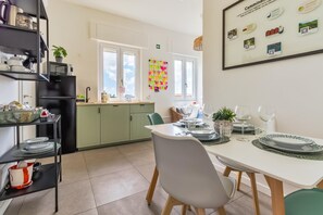 Een moderne keuken met een eethoek, met een witte tafel gedekt met borden, glazen en een potplant.