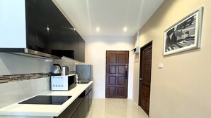 A modern kitchen with a built-in stove, microwave, and coffee maker. - Sea View Studio With Large Balcony at View Talay 5D (Pattaya)
