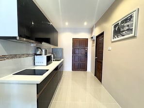 A modern kitchen with a built-in stove, microwave, and coffee maker. - Sea View Studio With Large Balcony at View Talay 5D (Pattaya)