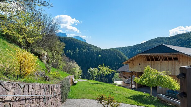 Un mur de pierre, un bâtiment en bois et un chemin pavé dans une région montagneuse.