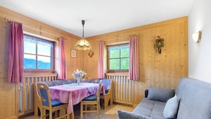 Un intérieur en bois comprenant une table à manger, des chaises, un canapé et des fenêtres avec des rideaux.