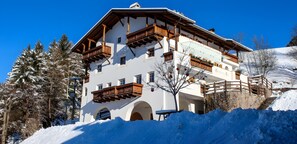 Un edificio a più piani con balconi, una scala in pietra e dintorni innevati.