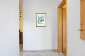 Ein Flur mit einem gerahmten Bild an der Wand, einer Holztür und einem gefliesten Boden.
