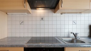 Una cocina con estufa negra, lavamanos y salpicadero de azulejos.