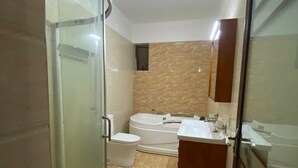 A modern bathroom with a glass shower enclosure, a toilet, a bathtub, and a vanity with a mirror. - Peaceful 4bed all-ensuite apartment in vibrant Nairobi (Nairobi)