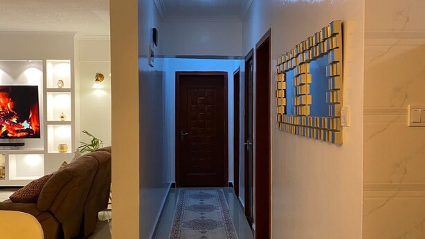 A modern living room with a flat-screen TV, a sofa, and a dining area with a table and chairs. - Peaceful 4bed all-ensuite apartment in vibrant Nairobi (Nairobi)