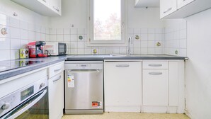 A kitchen with white cabinets, a microwave, a coffee maker, and a dishwasher. - Cocoon rose garden (L'Haÿ-les-Roses)