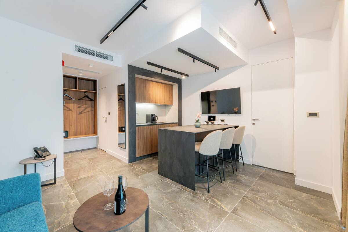 Una cocina moderna con una isla central, taburetes de bar y una zona de comedor con un sofá azul.