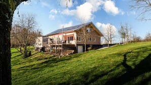 A house with a sloped roof, a covered porch, and a garage. - Holiday Home 'S'Lähmes Auf Der Schwend' with Mountain View, Private Terrace & Wi-Fi (Waldulm)