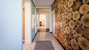 A hallway with a wooden wall of tree rings, a tiled floor, and a door leading to another room. - Holiday Home 'S'Lähmes Auf Der Schwend' with Mountain View, Private Terrace & Wi-Fi (Waldulm)