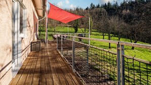 A wooden deck with a metal railing, a red canopy, and a view of a green landscape. - Holiday Home 'S'Lähmes Auf Der Schwend' with Mountain View, Private Terrace & Wi-Fi (Waldulm)