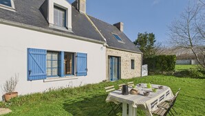 Una casa de piedra con contraventanas azules y un pequeño jardín.