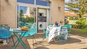 Un patio con sillas turquesa y una mesa, una lavadora y un salpicadero de azulejos.