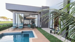 A modern outdoor pool area with a seating area and a large window overlooking the pool. - Elegance Santa Bárbara - Vacation Home at Santa Bárbara Resort Residence (Águas de Santa Bárbara)