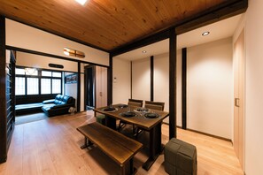 A dining area with a wooden table set for four, a bench, and a sofa in the background. - [Tsubame no Ie Tsuruhashi] 10-minute walk from Tsuruhashi Station | 8 minutes from Imazato Station | Namba, Umeda, Tennoji, Nara | Excellent transportation access (大阪市東成区玉津3丁目5)