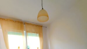 Makuuhuone, jossa on sänky, verhot, riippuvalaisin ja ikkuna.