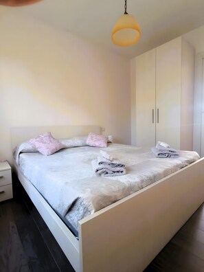 Ein Schlafzimmer mit Bett, Nachttisch, Kleiderschrank und Pendelleuchte.