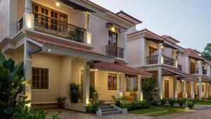 A multi-story house with a paved driveway and a well-maintained garden. - ELIVAAS Bauhinia 5 BHK Pvt Pool Villa  (Vagator)