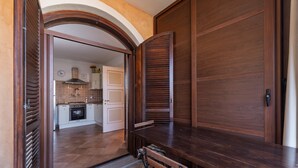 Ein Holzespeisezimmer mit Stühlen, ein offener Durchgang zu einer Küche und ein gefliestes Parkett.