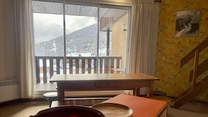 Une cuisine avec une table en bois et un saladier de fruits posé sur le comptoir.