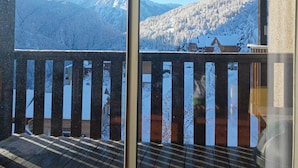 Un balcon offrant une vue sur des montagnes enneigées et un ciel dégagé.