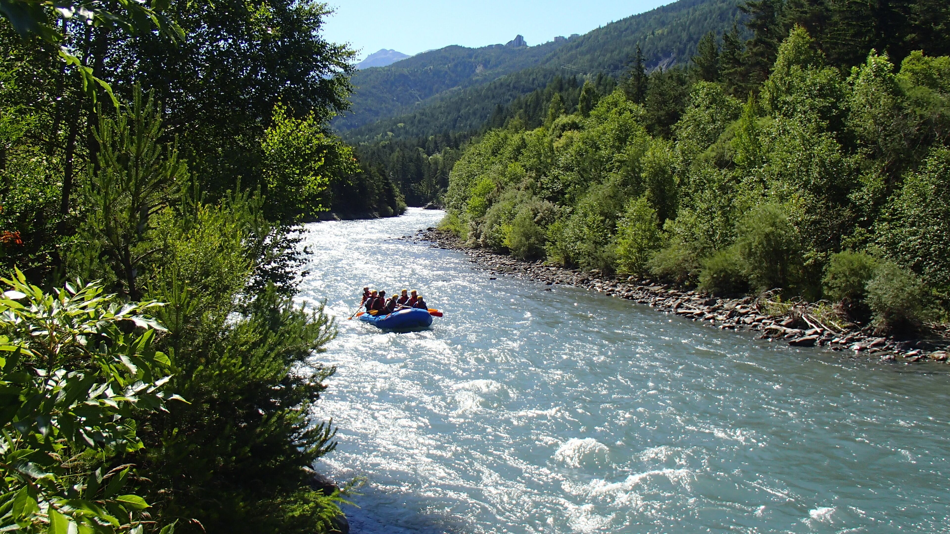 Une rivière où l’on voit un groupe de personnes faire du rafting.