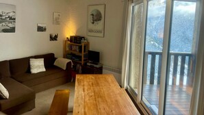 Un salon chaleureux avec une table en bois, un canapé marron et une bibliothèque.