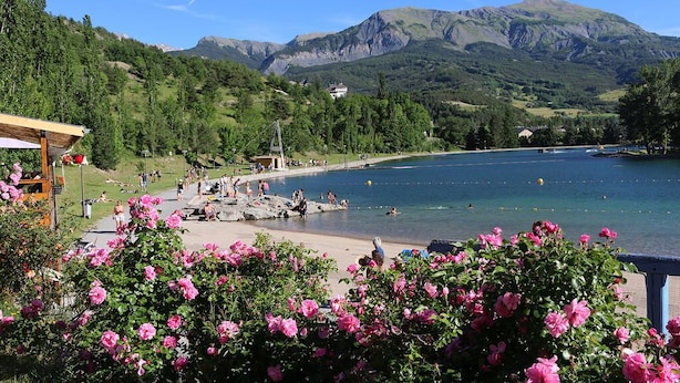 Une vue sur le lac, avec une terrasse en bois, un belvédère et une chaîne de montagnes en arrière-plan.