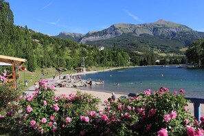 A lakeside view with a wooden deck, a gazebo, and a mountain backdrop.