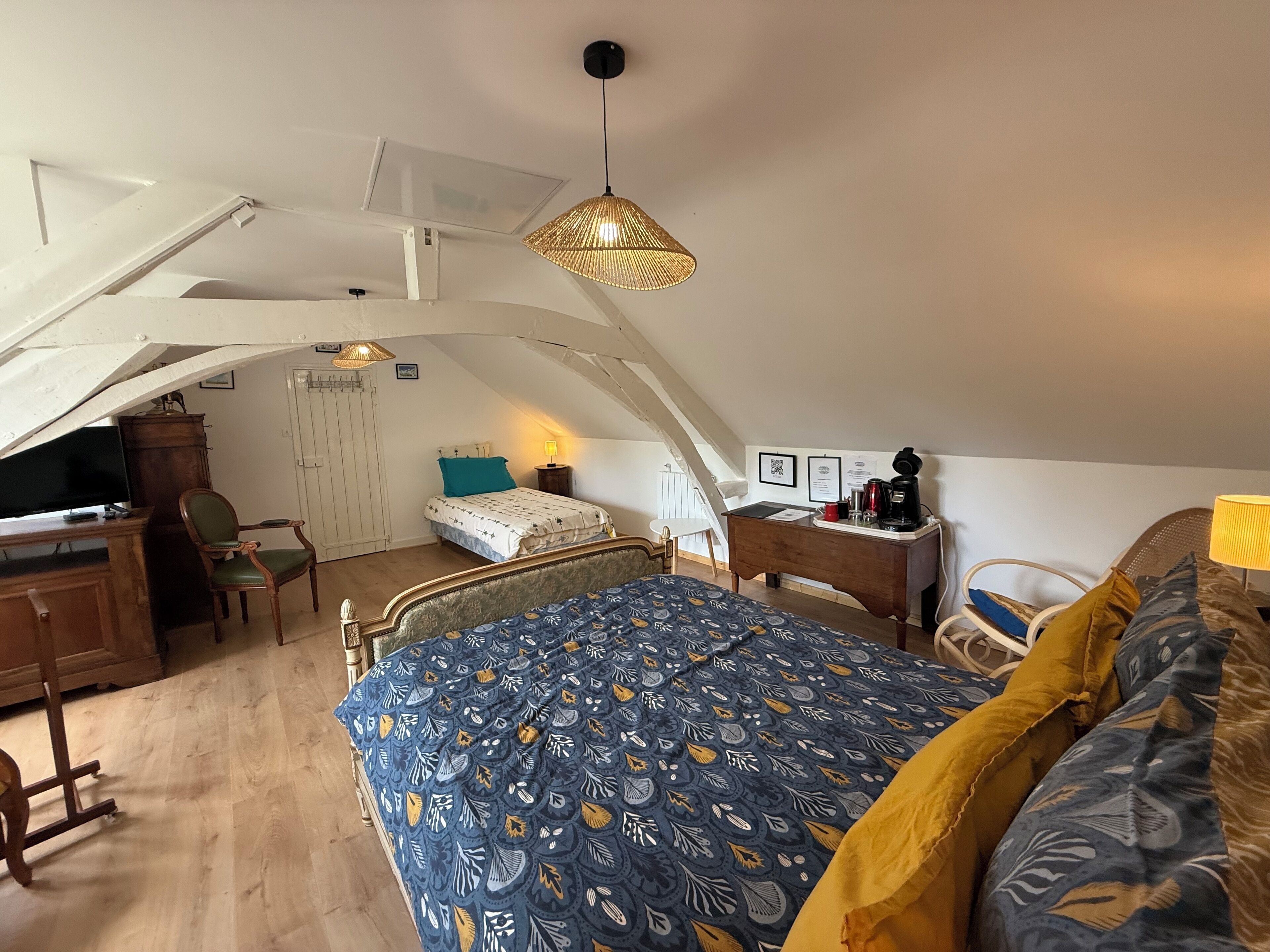 Ein Schlafzimmer mit Bett, Schreibtisch, Stuhl und einer Pendelleuchte.