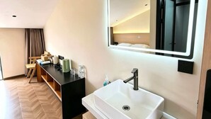 Ein modernes Badezimmer mit einem großen Spiegel, einem weißen Waschbecken und einem Waschtisch.