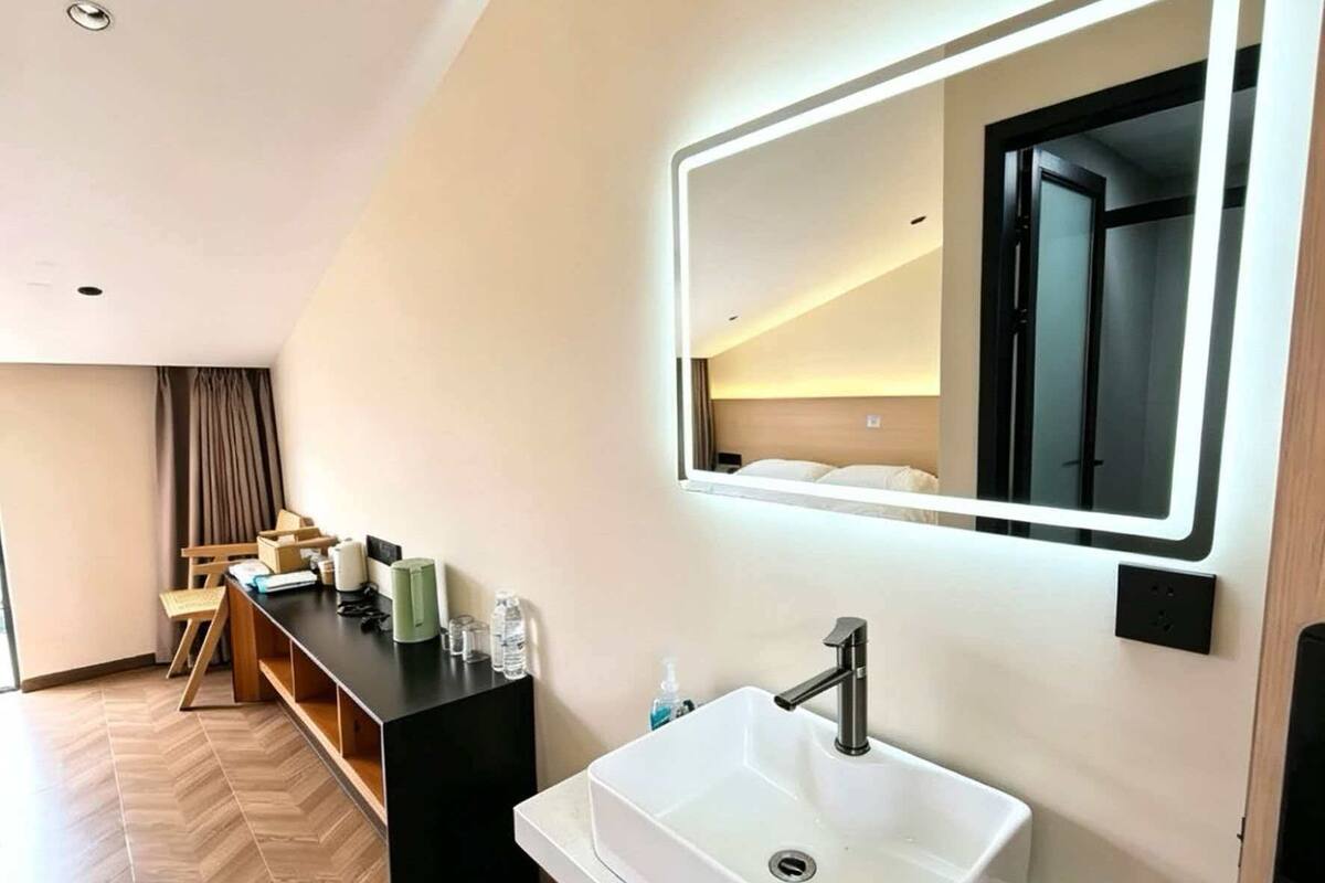 A modern bathroom with a large mirror, a white sink, and a vanity.