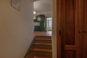 Un escalier menant à une cuisine avec des meubles de couleur verte et un sol carrelé.