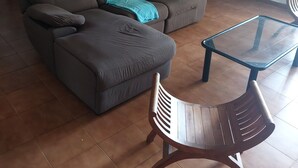 Un soggiorno con un divano marrone, un tavolino in vetro e una sedia di legno.
