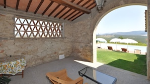 Ein Zimmer mit Blick auf einen Pool, Sitzgelegenheiten im Freien und einer Steinmauer.